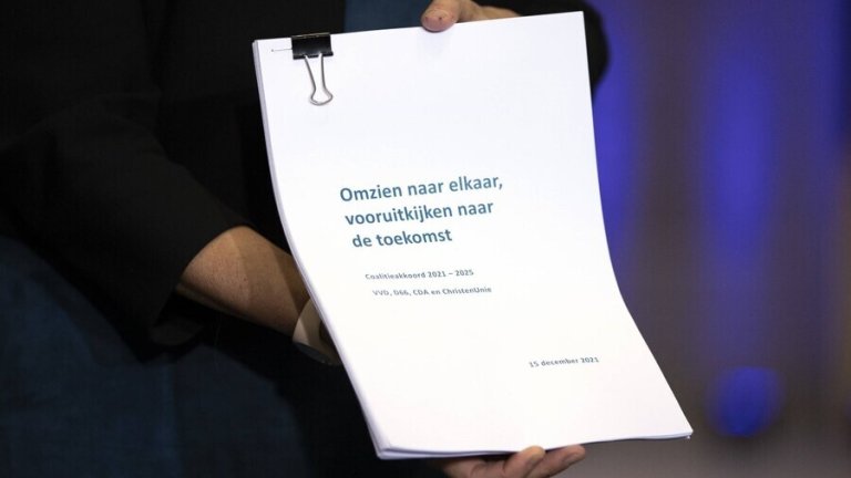 Hands holding Dutch Coalition agreement 2021