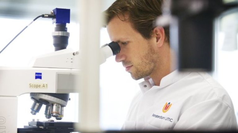 mannelijke onderzoeker kijkt door microscoop